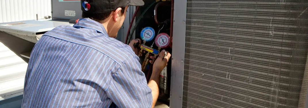 HVAC technician servicing a condenser unit in Elgin